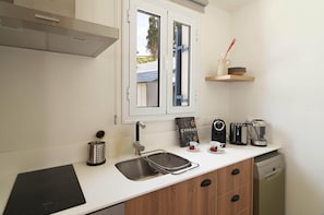 Eine kompakte Küche mit Spüle, Kaffeemaschine, Toaster und Geschirrspüler.