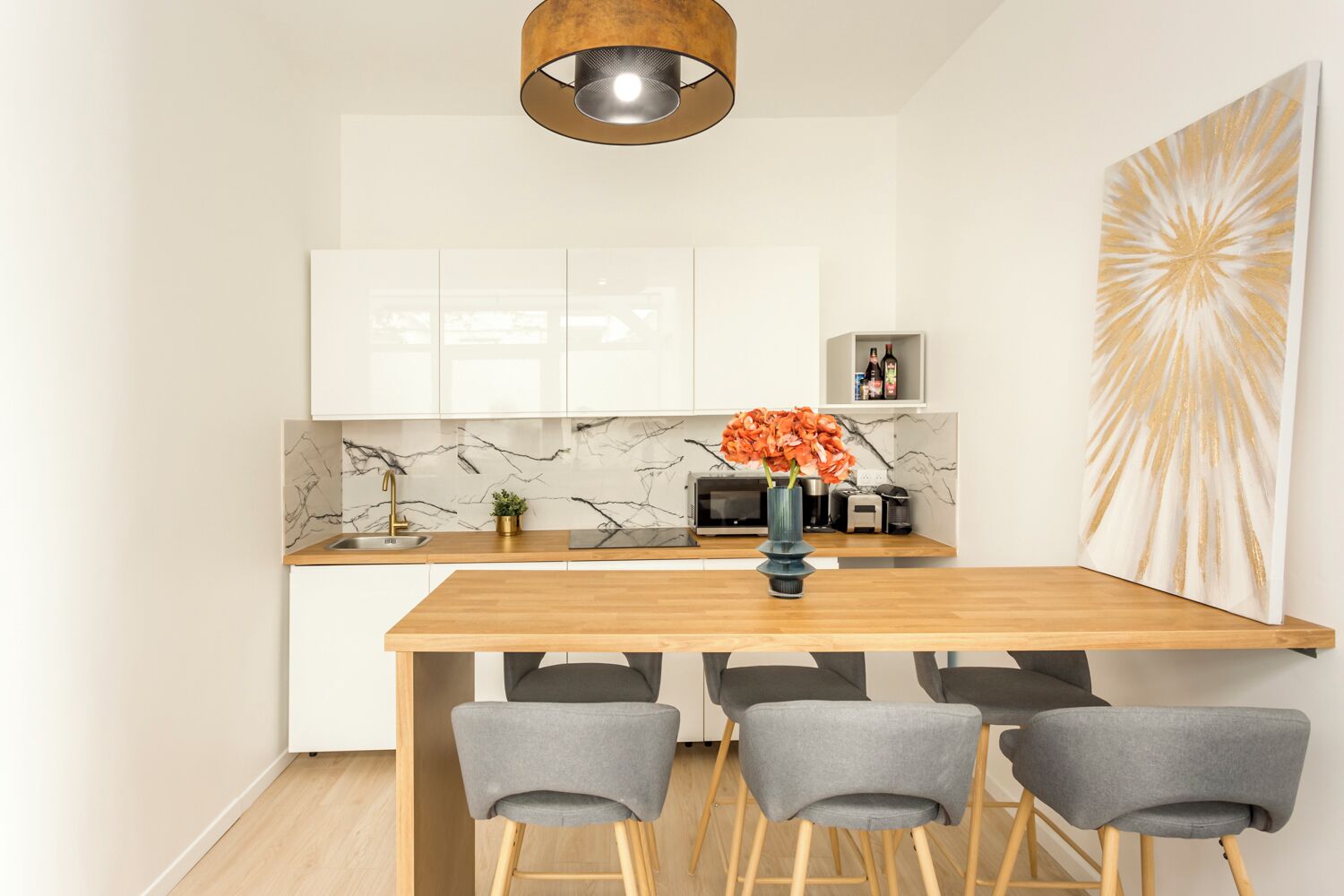 Een moderne keuken met witte kasten, een houten eiland en een groot abstract schilderij.