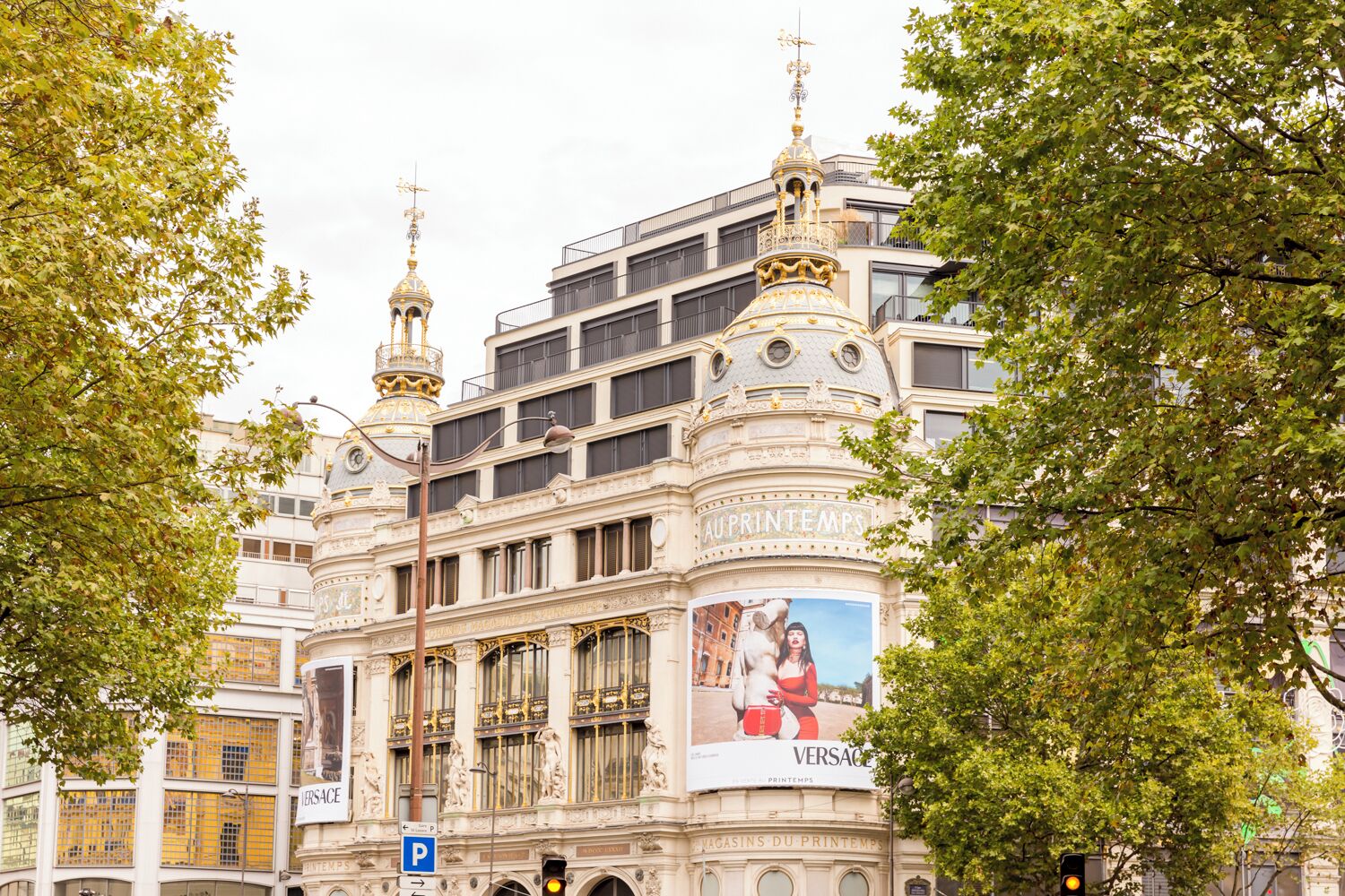 A historic building with ornate architecture, a prominent clock tower, and a large advertisement for a brand.