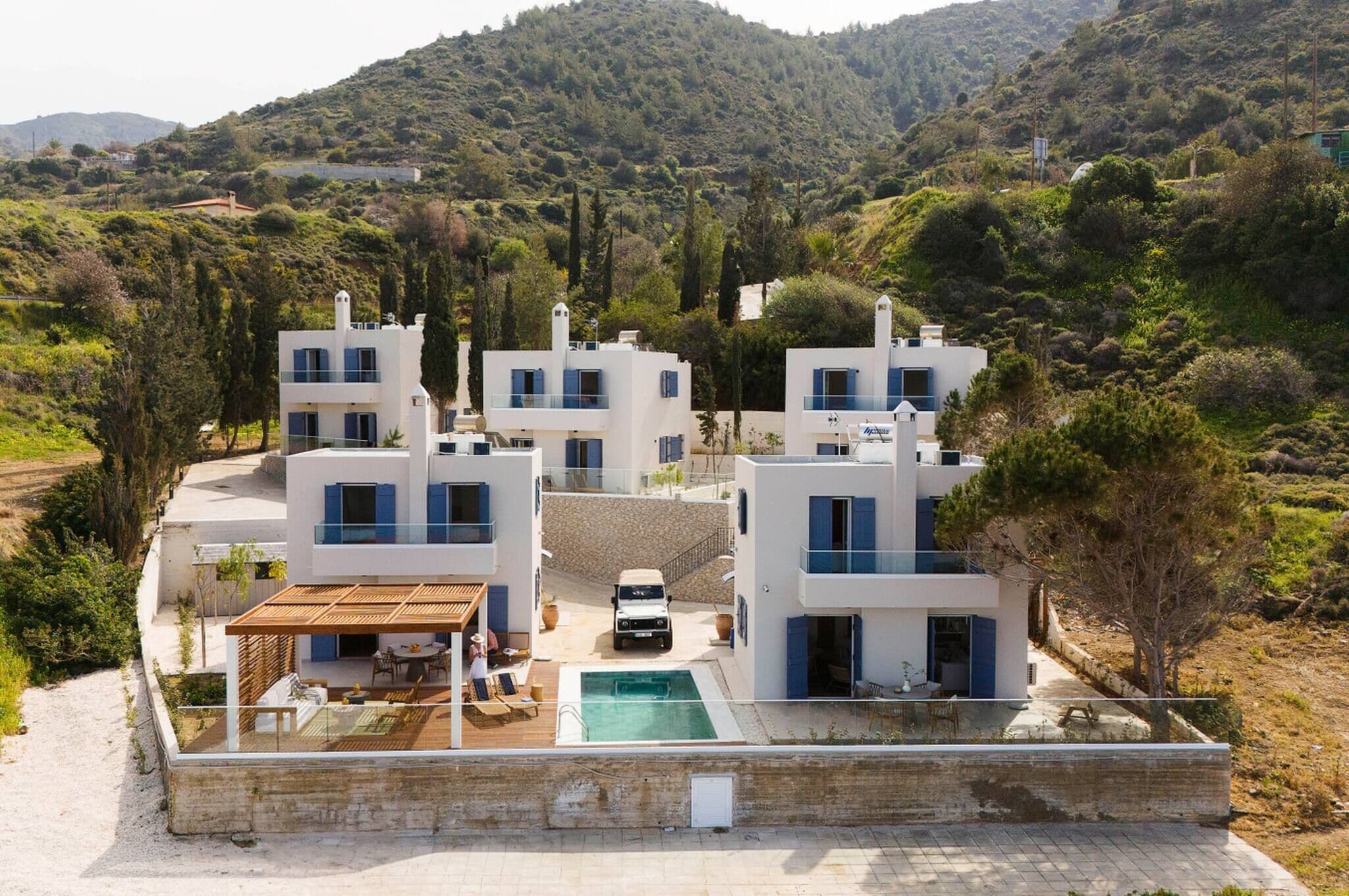 Una villa moderna con più livelli, una piscina e un'auto parcheggiata davanti.