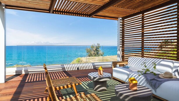Ein moderner Außenbereich mit Meerblick, ausgestattet mit einer Holz-Pergola, einer gepolsterten Couch und einem Korbstuhl.