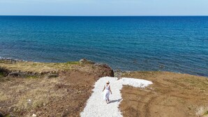 A person walking on a gravel path towards a body of water. - Villa Paradise | Coastal Calm at Moonlight Villas (Polis)