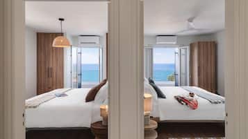 Habitación de hotel con dos camas, vista al mar y un balcón.