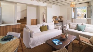 A spacious living area with a sofa, coffee table, and a dining table with chairs. A staircase is visible in the background. - Villa Paradise | Coastal Calm at Moonlight Villas (Polis)