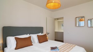 A neatly made bed with white and brown pillows, a book on the bed, and a woven light fixture above. - Villa Paradise | Coastal Calm at Moonlight Villas (Polis)