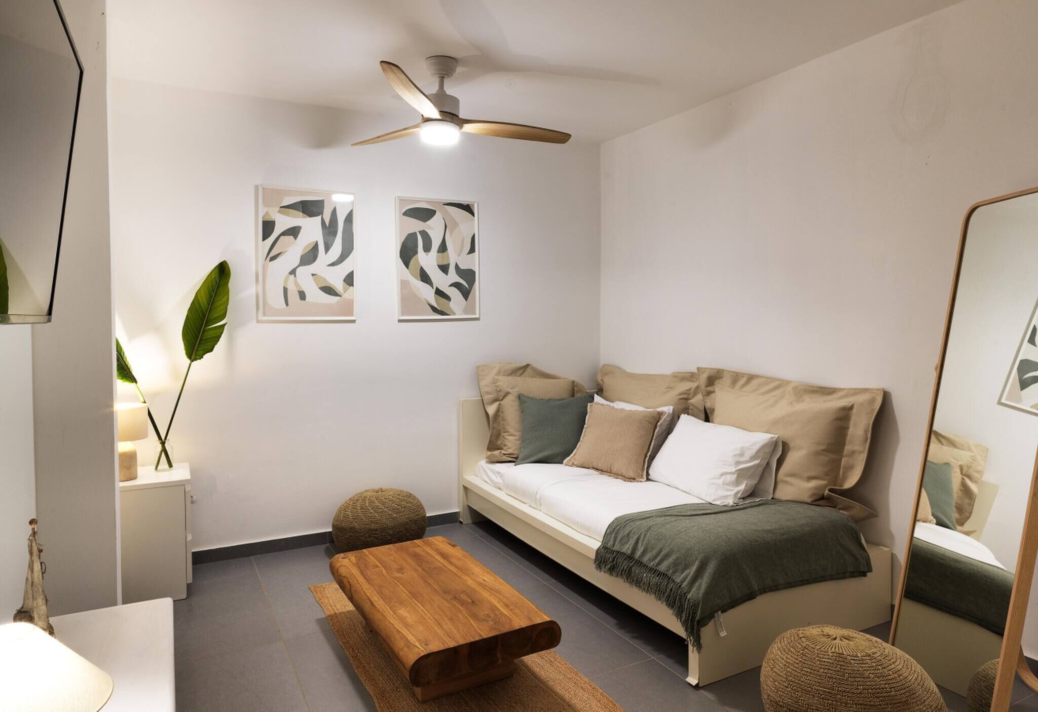 Uma sala de estar moderna com um sofá, um banco de madeira e um ventilador de teto.