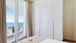 A bedroom with a large bed, a view of the sea, and a wardrobe. - Suite 1003 at Althea Residence (Larnaca)