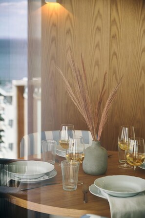 Una mesa de comedor dispuesta con copas de vino, platos y un florero con plantas secas.