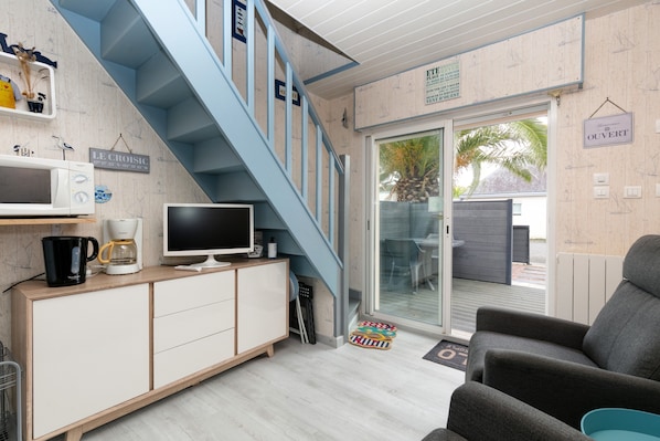 A modern living room with a staircase, a television, a coffee maker, and a sign reading 'OUVERT'. - Guest Room – Comfortable Stay Near Beaches, Harbor, and City Center (Le Croisic)