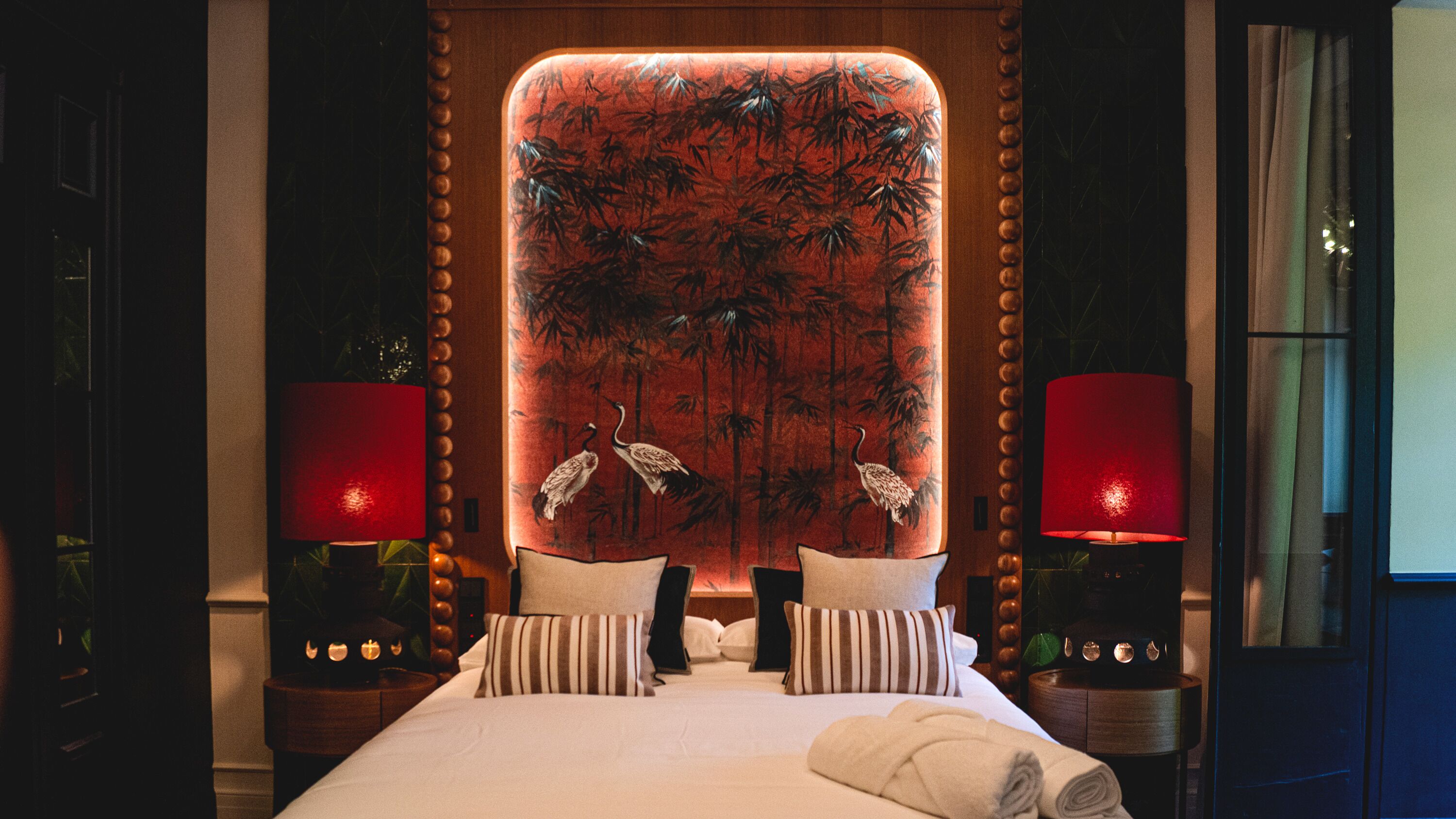 Una habitación de hotel con una cama grande, dos mesitas de noche con lámparas y un panel decorativo en la pared.