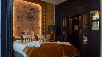 Habitación de hotel con cama, almohadas, lámpara y una pared con diseño de bambú.
