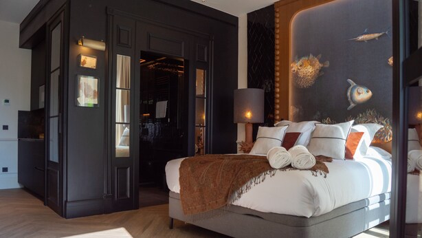 A modern bedroom with a large bed, a dark-toned wardrobe, and a mural of fish on the wall. - Boada Riera (Terrassa)