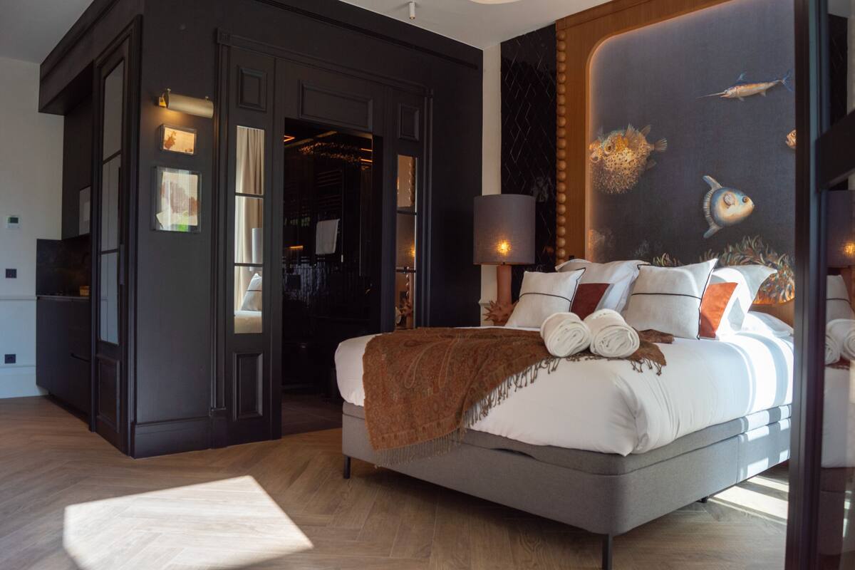 Un dormitorio moderno con una cama grande, un armario de tonos oscuros y un mural de peces en la pared.