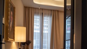 A hotel room with a dining area, a sofa, a lamp, a window with curtains, and a door. - Boada Riera (Terrassa)