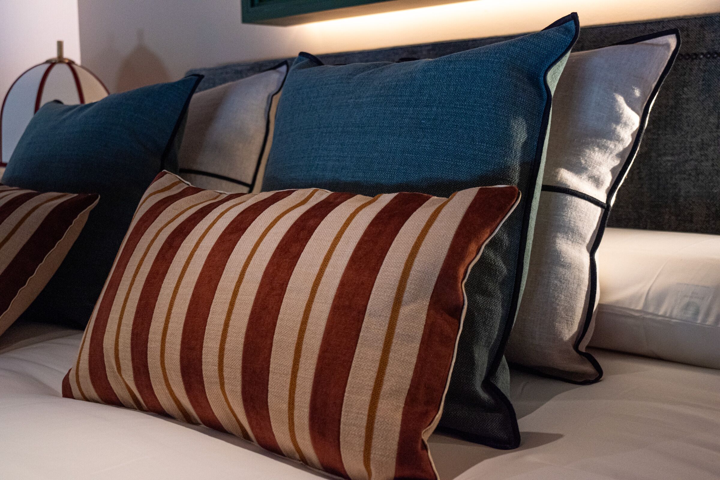 A bed with multiple pillows in various colors and textures.