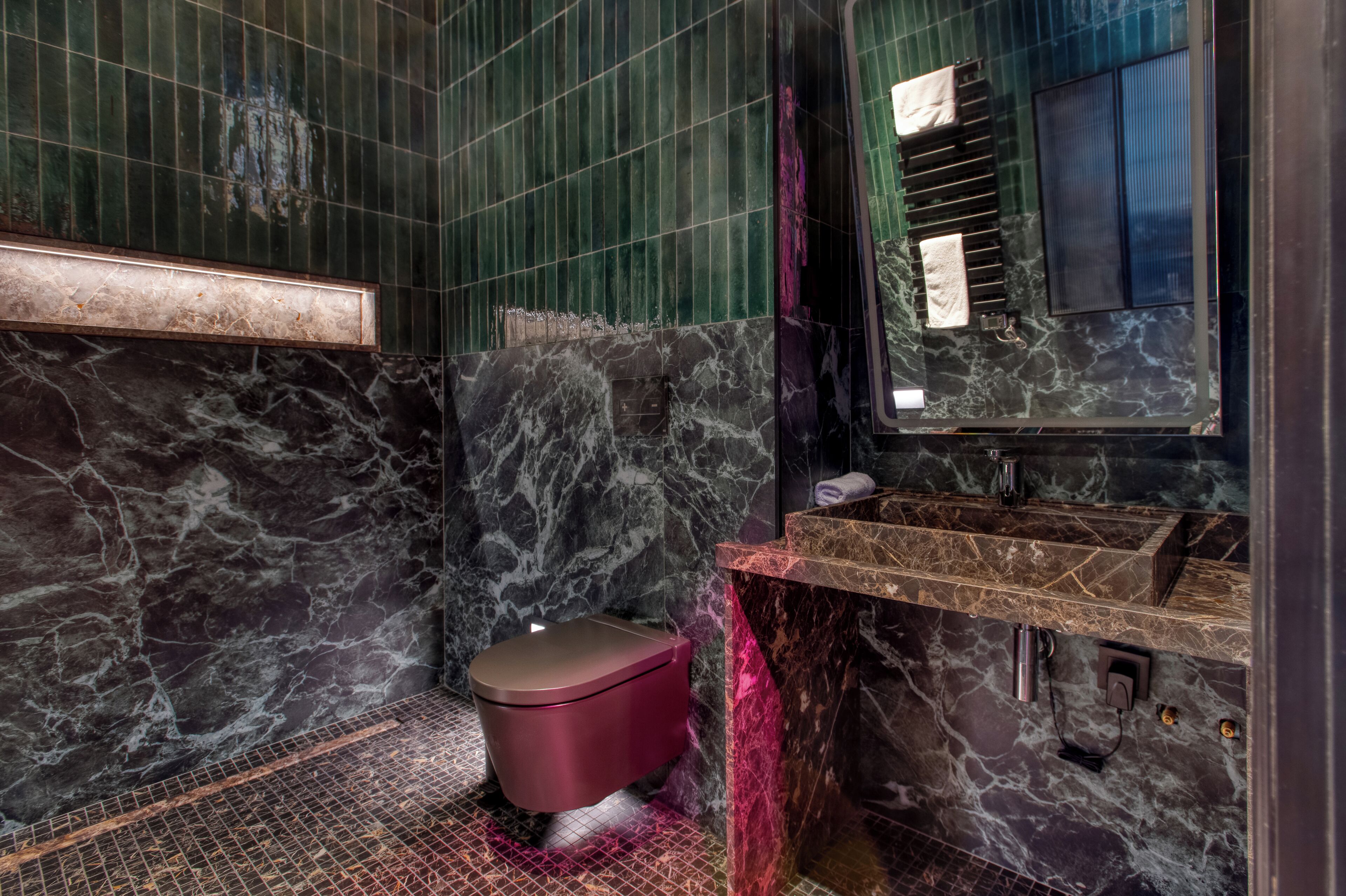 A bathroom with a marble sink, a toilet, and a mirror.