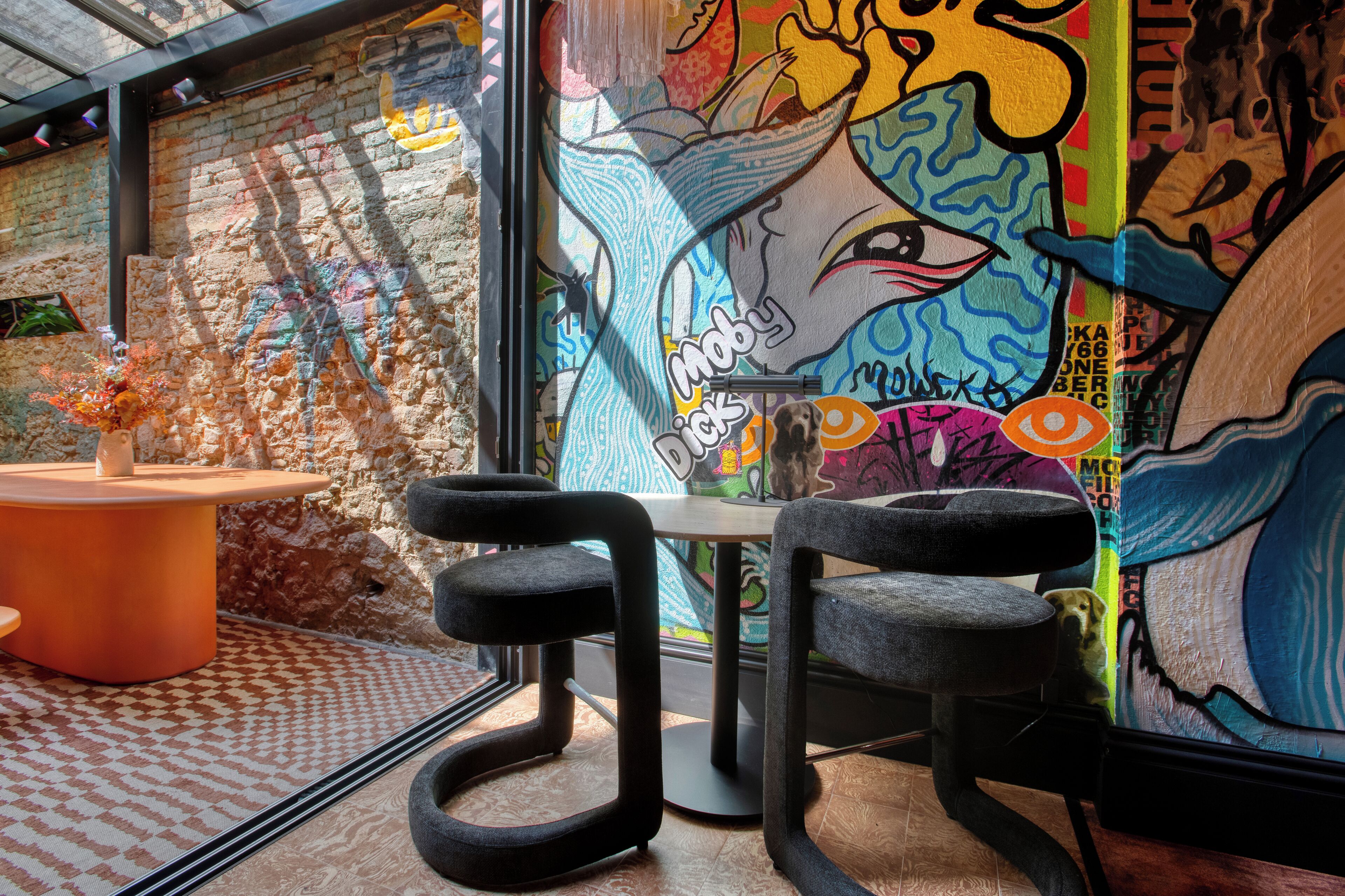 A modern interior with a mural, a round table, and two black chairs.