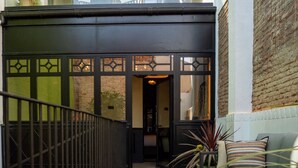A modern entrance with a black gate, a staircase, and a seating area with patterned cushions. - Boada Riera (Terrassa)