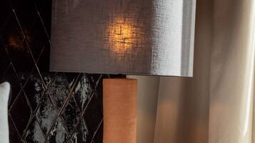 A modern lamp with a textured shade and a unique, spiky base on a wooden nightstand.