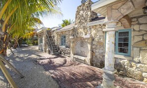 A stone building with a brick pathway, palm trees, and a stone staircase. - The Hideaway - Less than a block from beach! (Anna Maria)