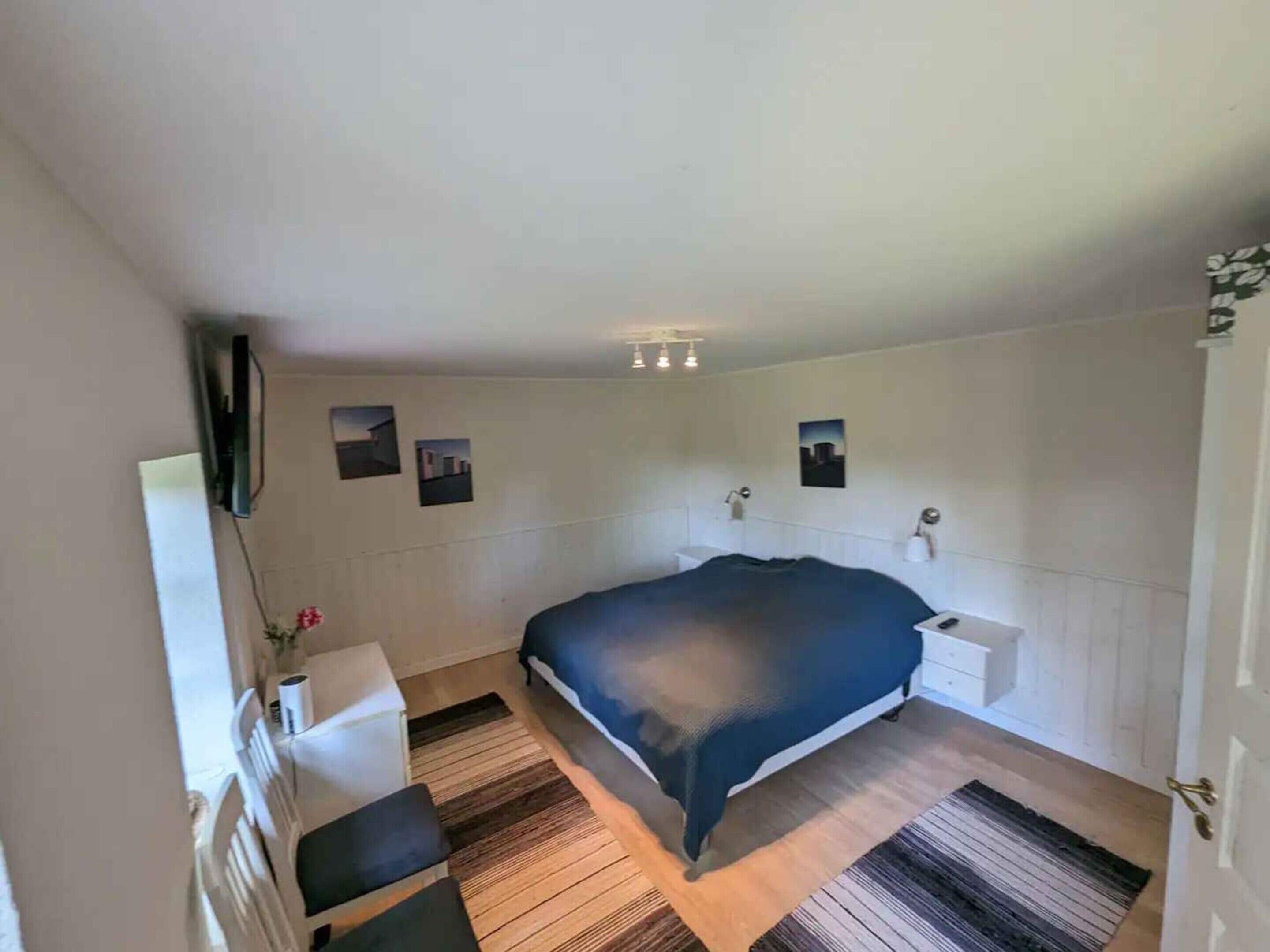 A bedroom with a bed, bedside tables, a mirror, and a wall-mounted TV.