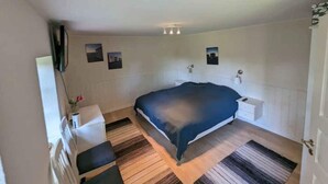 A bedroom with a bed, bedside tables, a mirror, and a wall-mounted TV. - 5 Star Holiday Home in Vesterborg (Vesterborg)