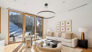 Un salon moderne doté d’une grande porte-fenêtre coulissante donnant sur un balcon, d’un canapé blanc, d’une table basse et d’une lampe.