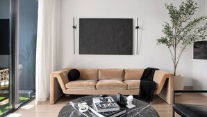 A modern living room with a beige sofa, a marble coffee table, a large abstract painting, and a potted plant. - The first choice-vacation rental (Atlanta)