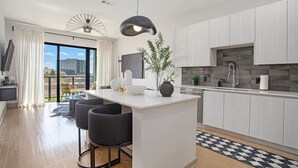 A modern kitchen with a central island, bar stools, and a view of the city through large windows. - The first choice-vacation rental (Atlanta)