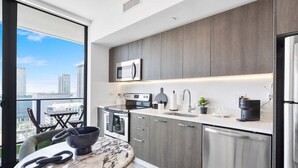 A modern kitchen with a large window, a marble countertop, and a city view. - Downtown Miami Getaway (Miami)