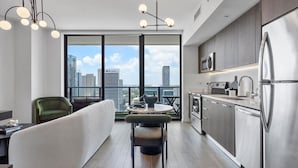 A modern kitchen with stainless steel appliances, a dining area with a round table and chairs, and a large window offering a city view. - Downtown Miami Getaway (Miami)
