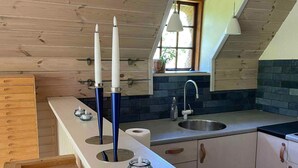 Una cucina con soffitto in legno, una finestra vista, un lavello e un piano di lavoro con candele e una bottiglia.