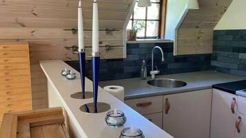 Una cucina con soffitto in legno, una finestra, un lavandino e un bancone con candele.