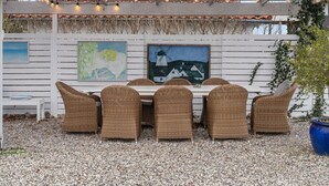 An outdoor dining area with wicker chairs and a table, under a pergola with string lights. - 5 Star Holiday Home in Hornbaek (Hornbaek)