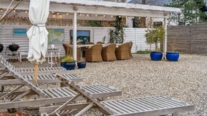 A patio area with wooden lounge chairs, a white umbrella, and a pergola with string lights. - 5 Star Holiday Home in Hornbaek (Hornbaek)