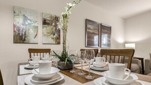 Une table à manger dressée avec de l’assiette blanche, des tasses et des verres, entourée de chaises.