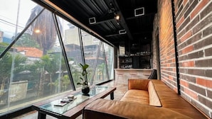 A modern interior with a glass wall, a leather sofa, and a small table with a plant. - Hotel Lleras Park III (Medellín)