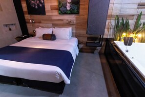 Una camera d'albergo moderna con un letto grande, una testiera in legno e un comodino con una lampada.