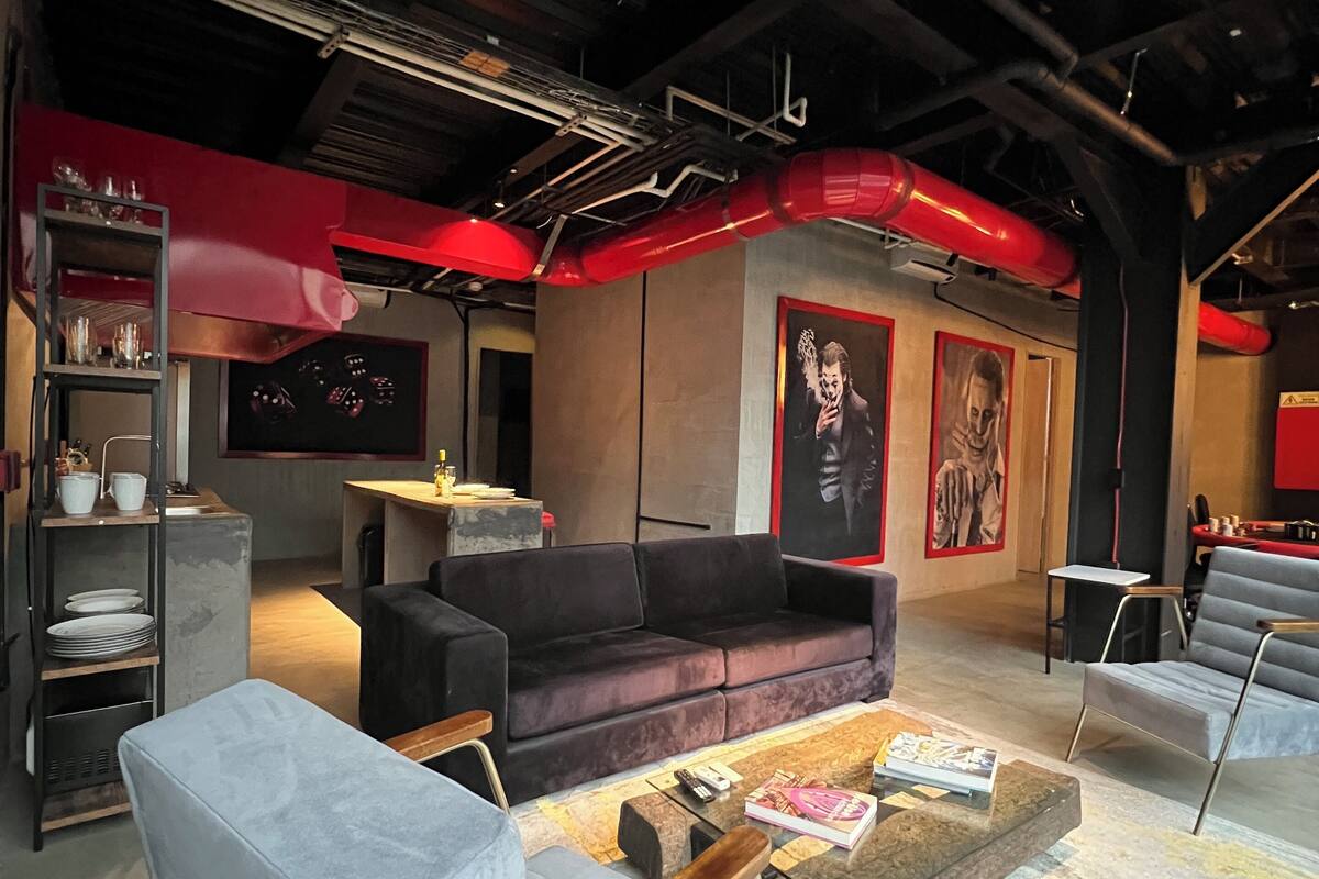 A modern interior with a dark ceiling, red accents, a grey sofa, a coffee table, and a bookshelf.