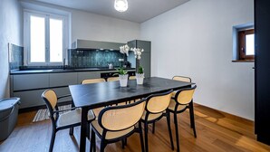 Eine moderne Küche mit Essbereich, ausgestattet mit einem schwarzen Tisch, Korbstühlen und Topfpflanzen.