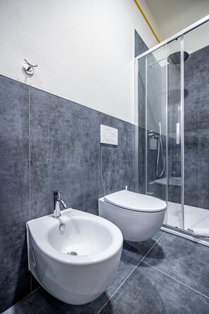 Un baño moderno con un bidé, un inodoro y una ducha con cerramiento de vidrio.