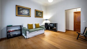 Una sala de estar con un sofá, un mueble para la televisión y dos cuadros en la pared.