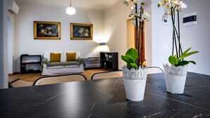 Ein modernes Wohnzimmer mit einem schwarzen Marmortisch, zwei weißen Orchideenvasen, einem Sofa und einer Lampe.