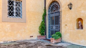 A building with a wrought iron gate, a window with a metal grille, and a small statue in a niche. - Dante's Paradise with a View of Florence (Firenze)
