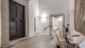 A hallway with a wooden door, a light fixture, and a vase with dried plants. - Dante's Paradise with a View of Florence (Firenze)