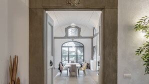 An interior view of a dining area with a high ceiling, a large arched window, and a chandelier. - Dante's Paradise with a View of Florence (Firenze)