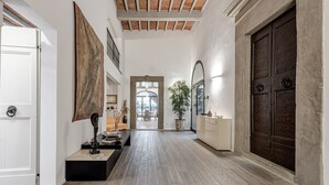 A spacious hallway with a wooden floor, a large dark wooden door, and a potted plant. - Dante's Paradise with a View of Florence (Firenze)