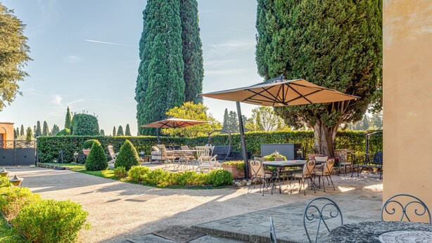 An outdoor patio area with stone flooring, round tables, chairs, and umbrellas. - Dante's Paradise with a View of Florence (Firenze)