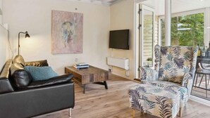 A modern living room with a sofa, a coffee table, a patterned armchair, a painting on the wall, and a TV. - 4 Star Holiday Home in Hemmet (Hemmet)