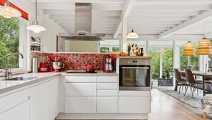 A modern kitchen with white cabinetry, a red kettle, and a built-in oven. - 4 Star Holiday Home in Hemmet (Hemmet)